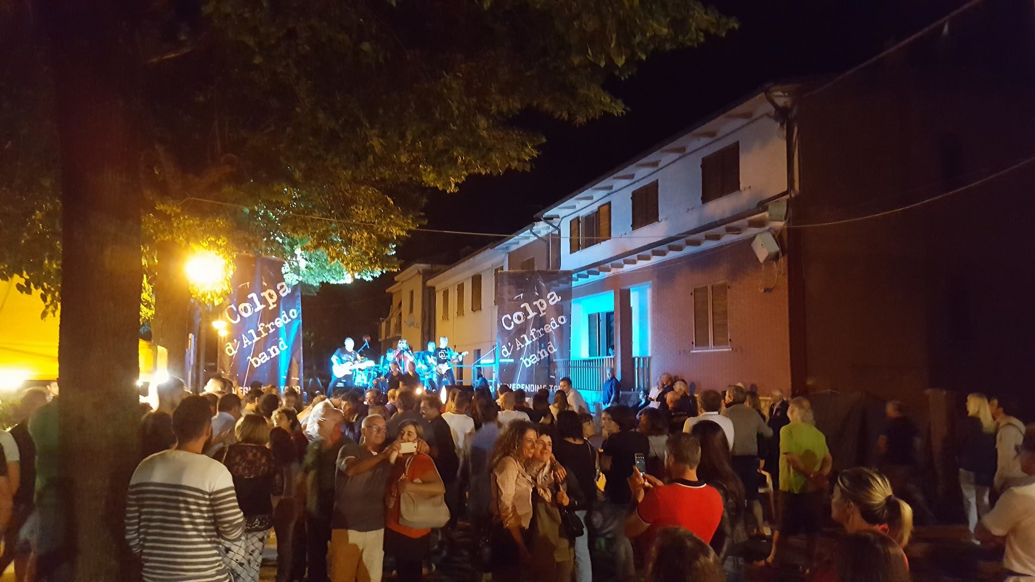 Persone riunite davanti al palco durante un concerto serale