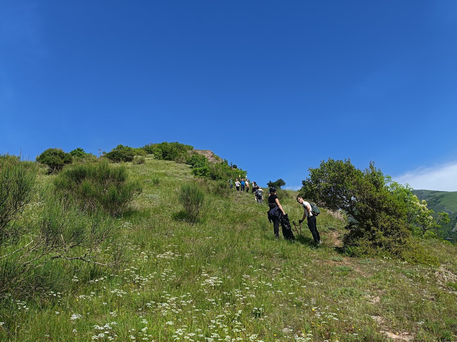 Escursionisti percorrono un sentiero tra i prati delle montagne di Pianello