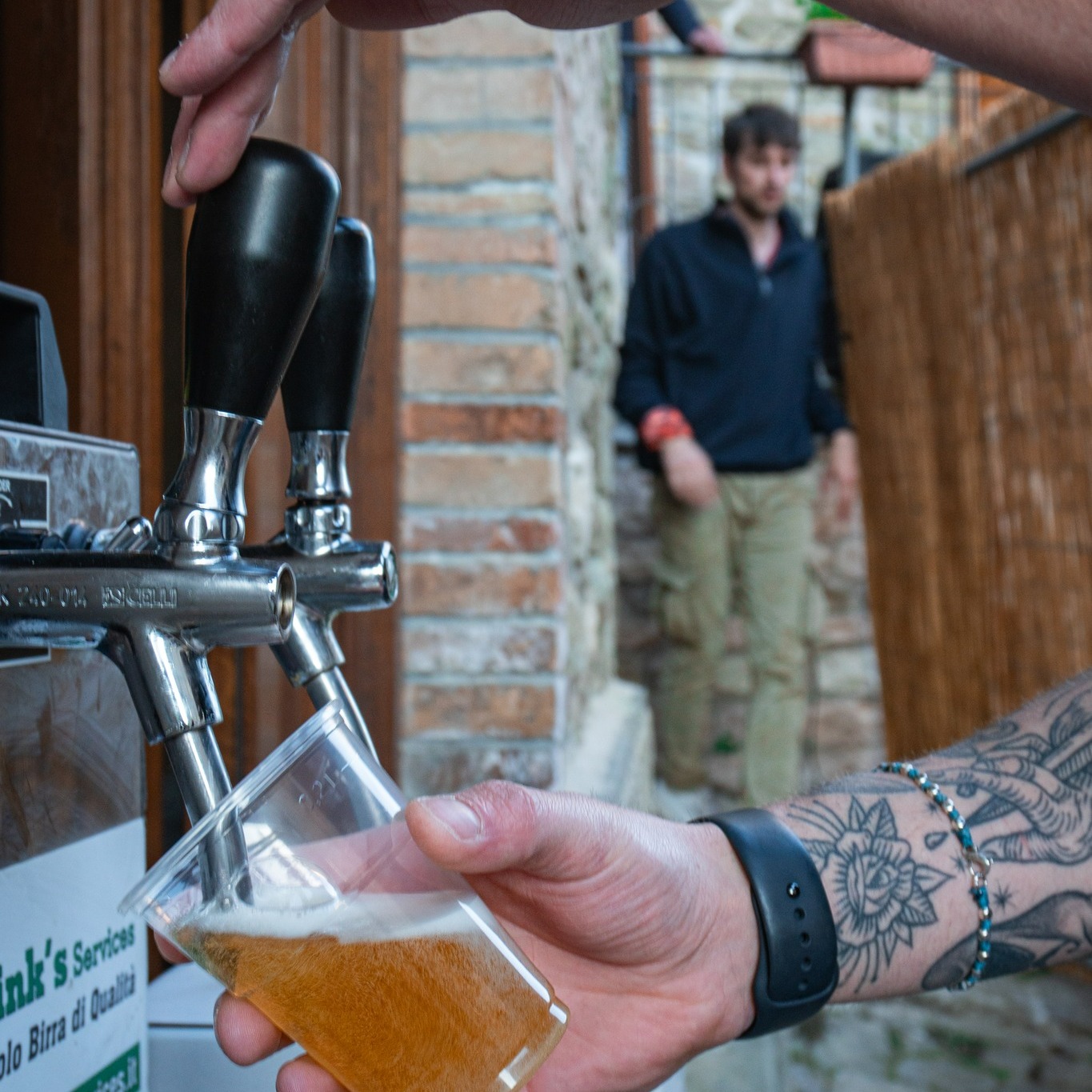 Una mano sorregge un bicchiere mentre viene spillata la birra