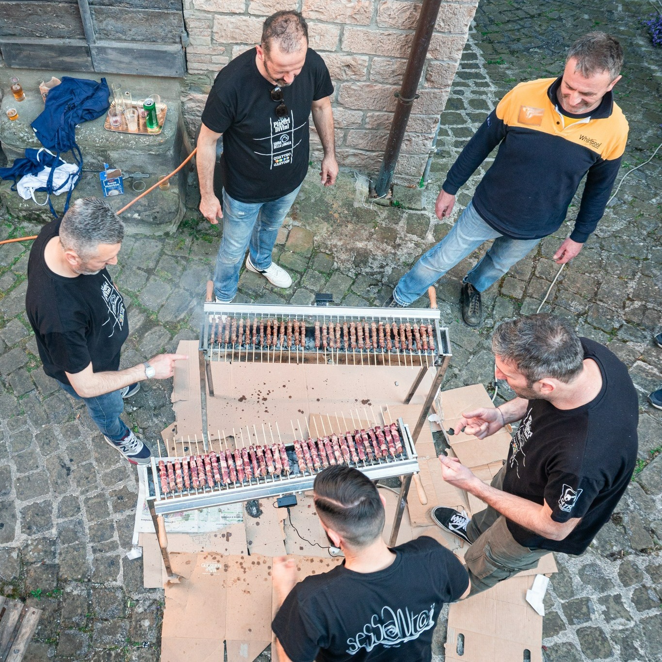Volontari preparano gli spiedini sulla griglia